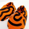 Orange baby crib shoes with a black squiggle