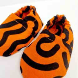 Orange baby crib shoes with a black squiggle