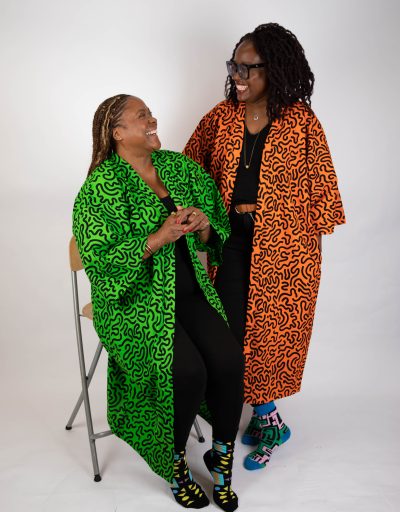Two smiling ladies model By Kala X long kimono style jackets